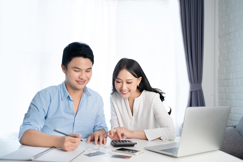 Asian couples are calculating their expenses with a calculator They are happy