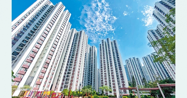 Cluster of tall residential high rrise buildings with a bright blue sky and greenery at ground level viewed from below toward the skyline
