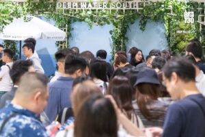 Crowd of people at a Deep Water South booth decorated with green vines and a white umbrella