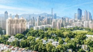 A city skyline with tall buildings rising behind a tree filled park in the foreground