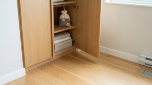 Open wooden cabinet with folded towels on the lower shelf and a small drawstring bag on the middle shelf