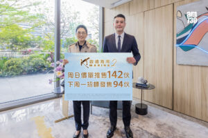 Two people in business attire pose indoors holding a large sign with Chinese text and the word MARINA