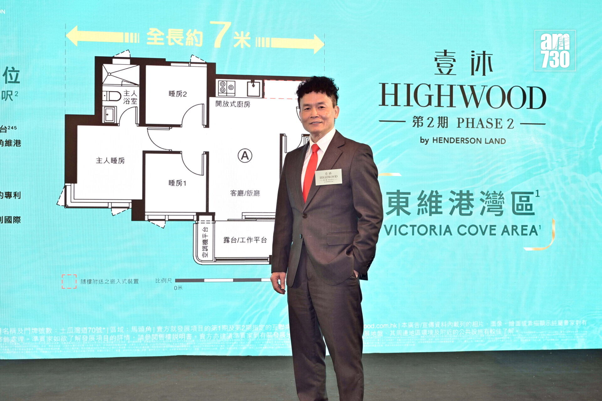 Man in a suit poses in front of a blue real estate backdrop with a floor plan diagram and 'HIGHWOOD' branding