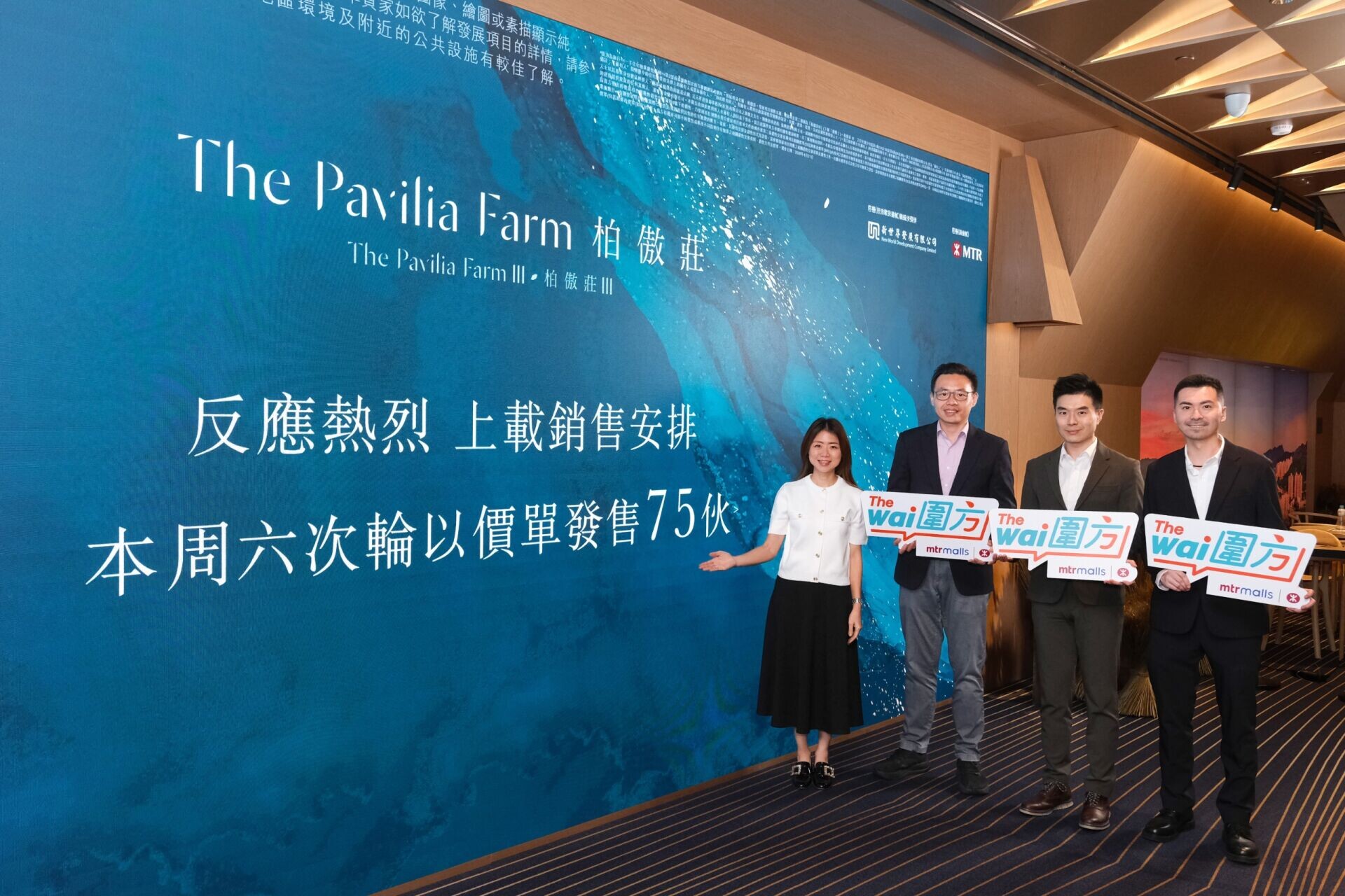 Group of four adults in business attire posing with signs in front of a blue backdrop with 'The Pavilia Farm' branding and Chinese text (event photo).