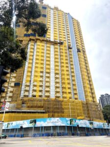 High rise building under construction with yellow safety nets and blue glass panels street level with construction barriers and banners reading CLOUDVIEW