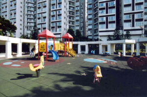 01017d | 利嘉閣地產有限公司 Colorful childrens playground with red roofed structures yellow slides and climbing equipment set against tall apartment buildings in a residential complex