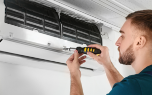 Technician tightening screws on a wall mounted air conditioner with a screwdriver