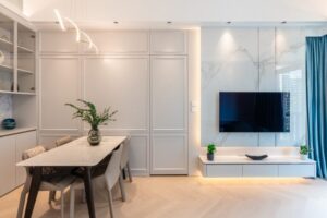 Modern dining area with marble topped table beige chairs gray paneled wall and a wall mounted TV