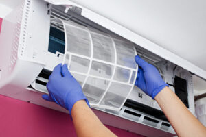 20210628022306200 | 利嘉閣地產有限公司 Hands wearing blue gloves insert a filter into a wall mounted air conditioner unit