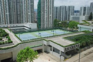 Tennis courts at Kornhill Recreation Club surrounded by tall apartment buildings and greenery in an urban complex
