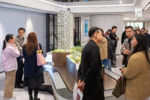 Group of people in a modern showroom admiring a detailed scale model of a high rise building