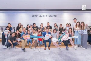 Large group photo of families and friends posing together at a Deep Water South event holding colorful signs and props