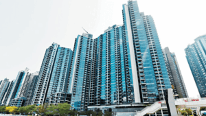 Cluster of tall blue glass residential towers in a modern city skyline with a pedestrian overpass in the foreground