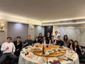 Group of coworkers at a banquet table posing with thumbs up after a meal in a formal restaurant setting