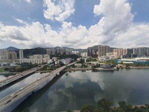 City skyline along a river with a bridge high rise buildings hills in the background and a partly cloudy sky