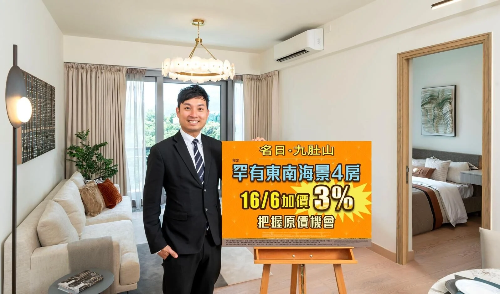 Smiling real estate agent in a suit stands beside an orange promotional sign in a bright living room.