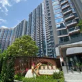 Tall modern high rise buildings with glass balconies against a blue sky foreground includes a sign reading MARINA with greenery
