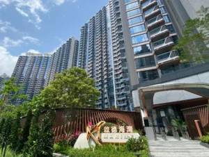 Tall modern high rise buildings with glass balconies against a blue sky foreground includes a sign reading MARINA with greenery