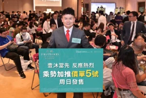Man in a gray pinstripe suit and red tie stands at a busy event holding a teal banner about Highwood Phase 2 as attendees chat in the background