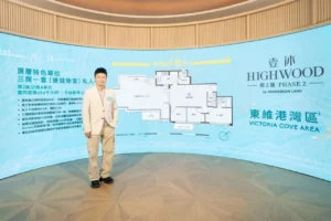 Man in light blazer standing in front of a blue curved real estate display with floor plan diagram and HIGHWOOD signage