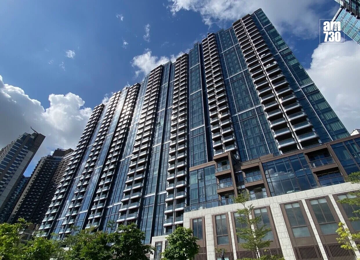 Tall modern glass high-rise under a blue sky with clouds; am730 logo in the top-right corner.