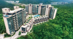 Modern hillside apartment complex with glass façades a central pool and surrounding green forest