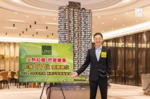 Asian man in a dark suit with a yellow Lime badge stands beside a tall high rise model and a green advertisement board in a showroom