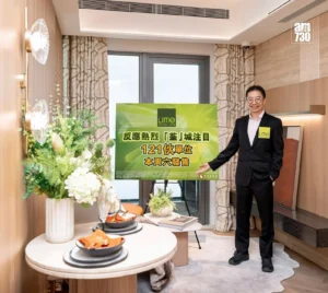 Man in a dark suit posing beside a lime green promotional sign in a showroom setting smiling at the camera with a floral arrangement nearby LIME Spark text on sign