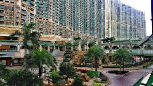 High rise apartment buildings with a landscaped courtyard and palm trees in the foreground shopping entrances at ground level