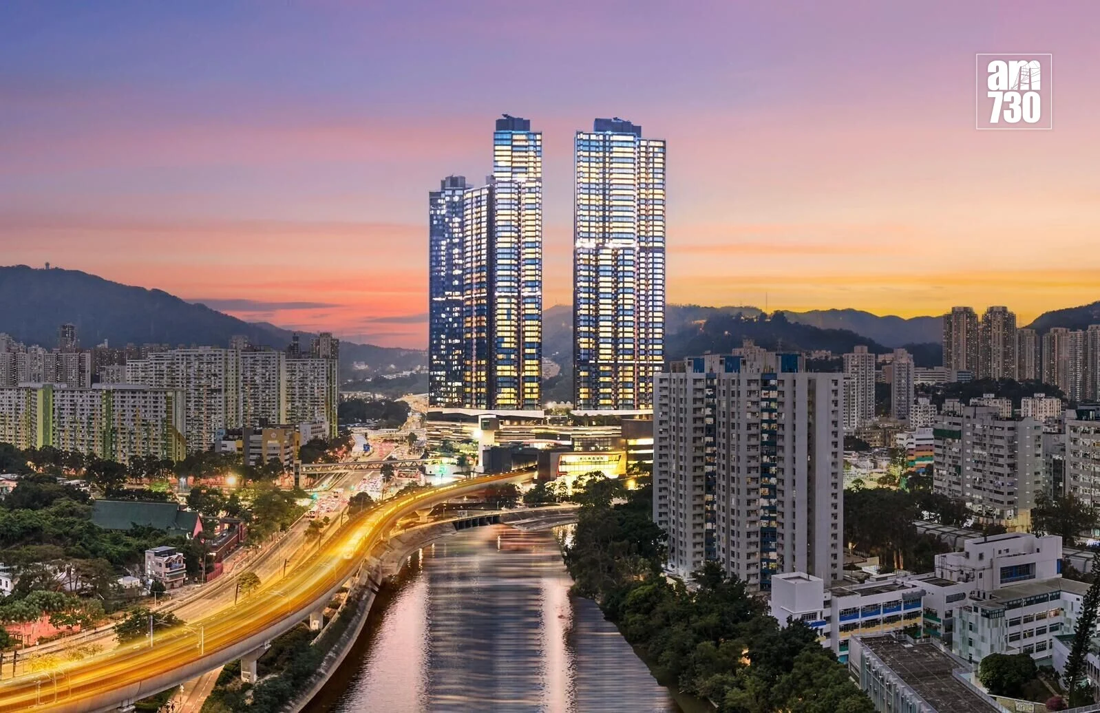 Twin glass skyscrapers dominate a city skyline at sunset beside a river, with a curved highway and surrounding high-rise apartments; AM730 logo in the top-right corner.