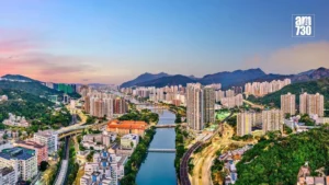 Panoramic cityscape with a winding river bridges and high rise buildings set among green hills at sunset am730 logo in the top right corner