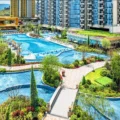 Luxurious resort complex with winding blue pools walkways and surrounding greenery beside high rise buildings