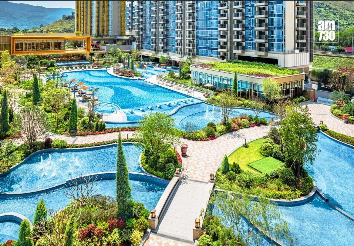 Luxurious resort complex with winding blue pools, walkways, and surrounding greenery beside high-rise buildings