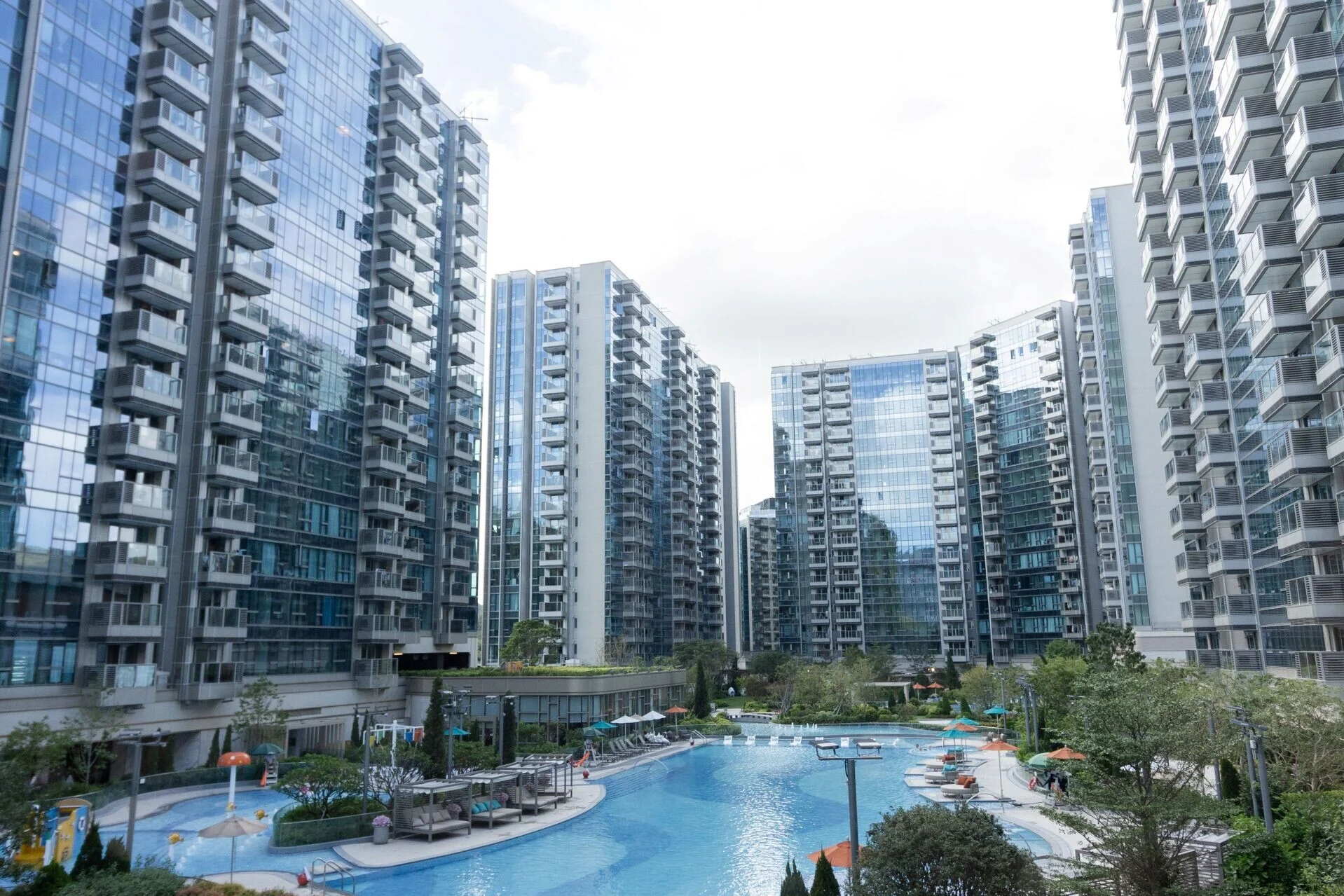 Cluster of glass fronted high rise apartment buildings surrounding a blue swimming pool courtyard