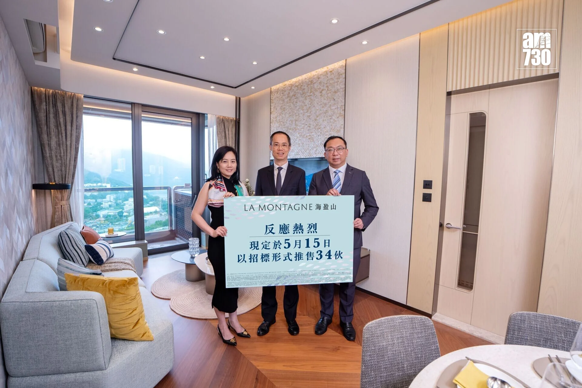 Three people in a modern living room hold a large blue poster with Chinese text.
