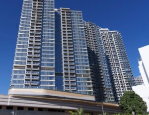 Tall glass high rise building set against a bright blue sky with am730 logo in the top right corner
