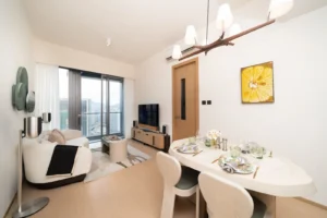 Open plan living and dining area with a city view balcony white furniture and a yellow flower painting on the wall