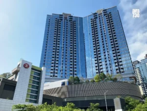 Tall blue glass office building with twin towers against a clear sky am730 logo visible in the top right corner